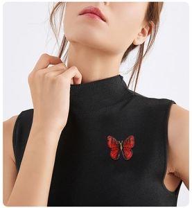 Gros plan détaillé d'une broche papillon rouge brodée sur un pull noir élégant
