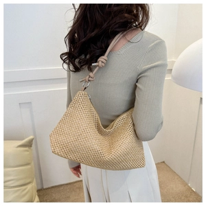Detail of khaki straw shoulder bag with knot strap design shown on model shoulder