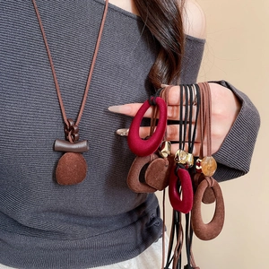 Detailed view of vintage flocked resin geometric pendants on adjustable suede cords