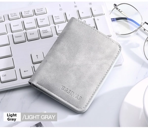 Detail view of a slim light gray textured wallet on a desk with office accessories