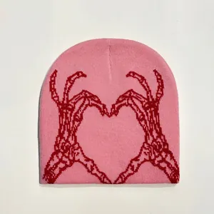 Pink knitted beanie featuring red skeleton hands forming a heart shape jacquard pattern