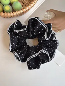 Detail view of black and white polka dot four-layer ruffled scrunchie with lace edge
