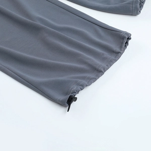 Détail du pantalon gris foncé montrant le cordon de serrage réglable et la texture du tissu