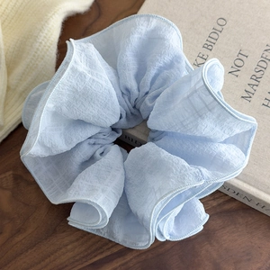 Detail of light blue plaid oversized scrunchie on wood with cozy knit background