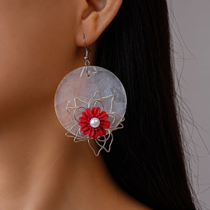 Detail of floral earring featuring translucent shell base, red flower and white pearl