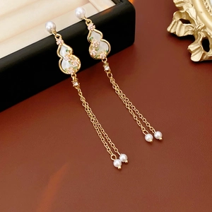 Detailed view of gourd-shaped gold earrings with faux pearl tassels and pink floral motifs