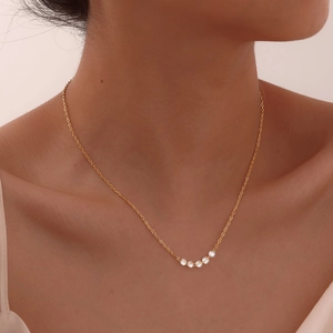 Elegant gold stainless steel necklace with five white zircons worn on woman's neckline