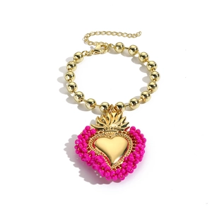 Detailansicht des Herzanhängers mit rosa Perlen und goldenen Kugeln am Armband