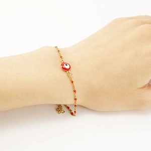 Evil eye bracelet with 18K gold plated chain and red beads worn on a female wrist