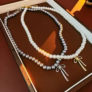 Collier de perles rétro français avec nœud doré sur fond de boîte à bijoux élégante
