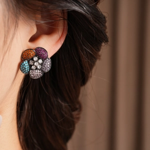 Close-up of vintage flower earrings with multicolor zircons worn by a model