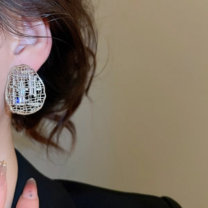 Gros plan d'une boucle d'oreille en maille dorée avec cristaux de zircon sur un mannequin