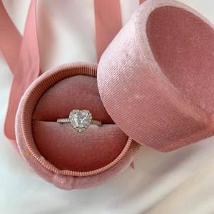Close-up of heart-shaped diamond silver ring in a pink velvet jewelry box with ribbon