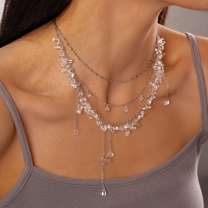 Detail of layered silver chain necklace with transparent irregular resin flower charms