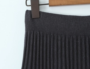 Detailansicht eines anthrazitgrauen Strickrocks mit Plisseefalten und elastischem Bund am Holzbügel
