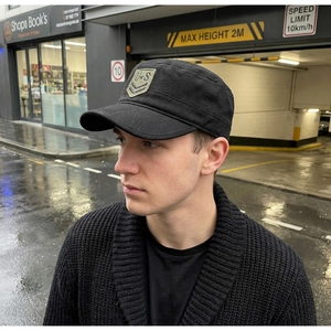 Detail shot of a black canvas cadet cap with U.S. embroidery and military rank patches