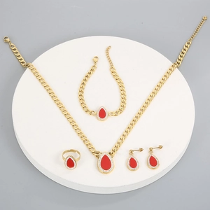 Detailed set of gold cubic chain jewelry with red teardrop stones on a white stand