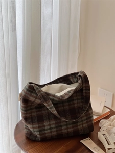 Gros plan du sac cabas en laine à carreaux marron montrant la texture sur table en bois
