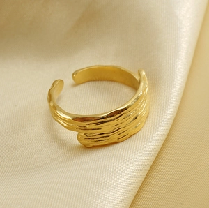 Detail of gold organic texture ring on champagne silk fabric showing premium metallic finish