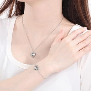 Silver stainless steel heart necklace and bracelet set shown on model with sparkling stones