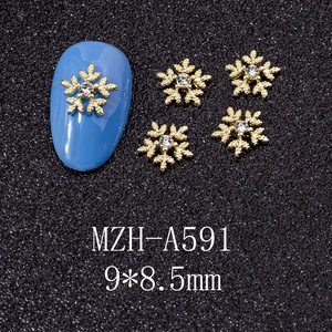 Macro shot of 9x8.5mm gold snowflake nail charms with rhinestones on a blue nail tip