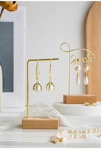 Detailed display of pearl gold earrings on a decorative stand with lace background