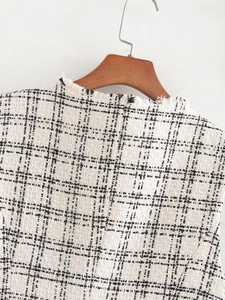 Detail of tweed vest with fringe neckline and premium black and white plaid texture