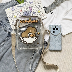 Flat lay of transparent PVC Capybara crossbody bag with cartoon duck illustration and strap