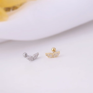 Macro shot of wing-shaped stud earrings in silver and gold with clear zircon stones