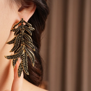 Close-up of vintage gold leaf earrings with black rhinestones worn by a model