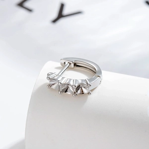 Silver hoop earrings with three round cubic zirconia stones on a soft blurred background