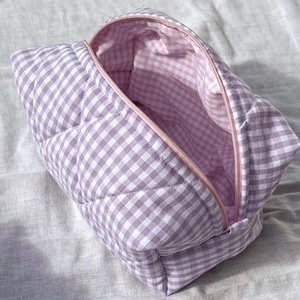 Detail of purple plaid quilted makeup bag with pink zipper and soft fabric lining