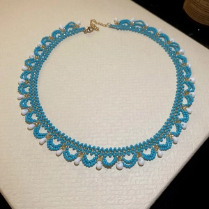 Detail of blue beaded lace necklace with white teardrop pendants and gold chain extender