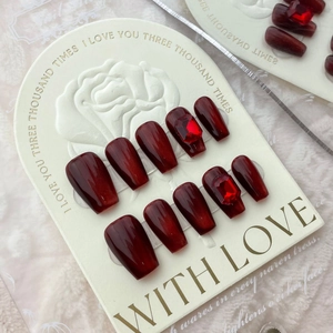 Handmade burgundy cat-eye press-on nails with red rectangle gemstone accents