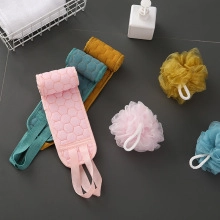 Detalle de esponjas de baño coloridas y exfoliantes de espalda sobre azulejo oscuro.