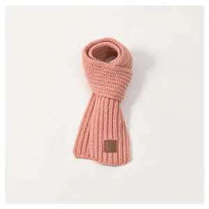 Detail of soft ribbed knit children scarf in pink featuring a vintage leather label