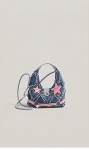 Close-up of Y2K style blue denim crossbody bag featuring pink star patches and embroidery