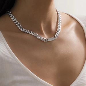 Silver cuban link chain necklace with rectangular metal plate on a white V-neck top