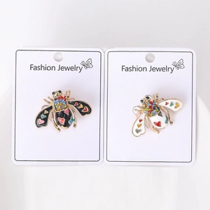 Detailed close-up of golden honey bee brooches with rhinestones on fashion jewelry cards