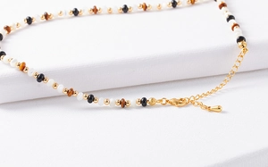 Close-up of beaded necklace with tiger eye stone, black onyx and gold metal beads detail
