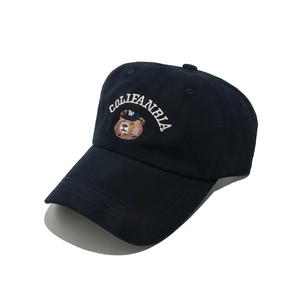 Dettaglio del cappello in cotone blu scuro con ricamo di orsetto e testo bianco