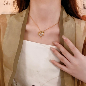 Detail of a vintage gold-plated fan pendant necklace with floral shell inlay on a model