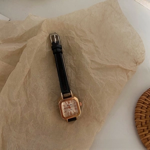 Detail view of retro square quartz watch with black leather strap on vintage background