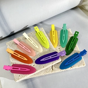 Set of 10 colorful matte oval seamless hair clips displayed on a decorative stone base