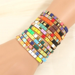 Stacked colorful Tila bead bracelets with gold accents on a model's wrist