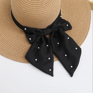 Detailed macro view of woven straw hat texture with black satin bow and white pearls