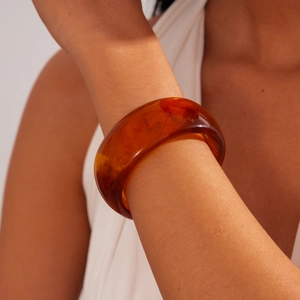 Macro shot of amber resin bangle showing detailed internal marbling and translucency
