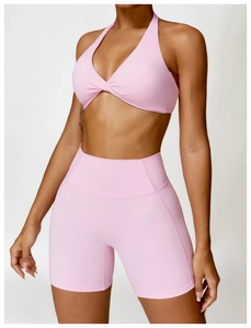 Detail of pink yoga set featuring a twist-front halter bra and high-waist sports shorts