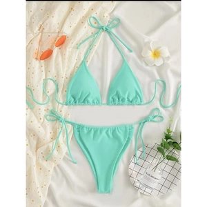Flat lay of mint green triangle bikini set with side-tie bottoms on summer beach props
