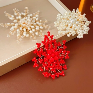 Detail of handmade woven pearl flower brooches in white, red and clear crystal on display